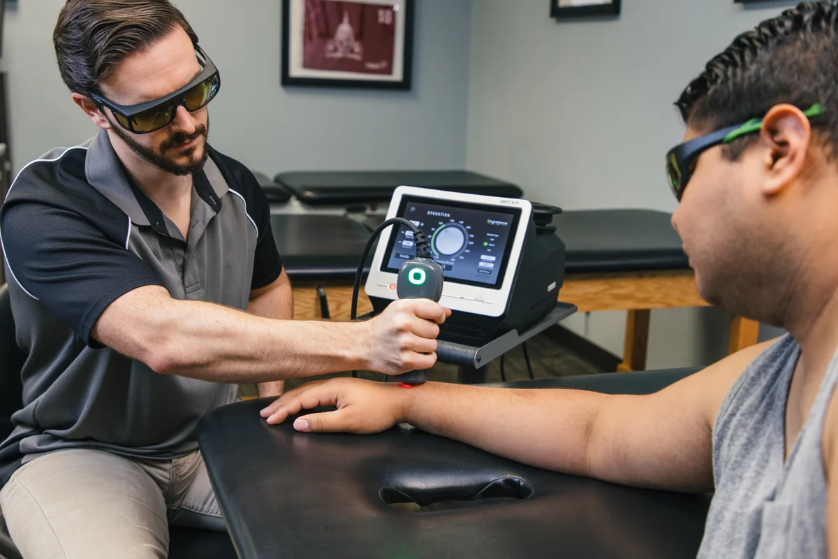Clinician demonstrating LightForce laser controls beside a patient wearing protective eyewear