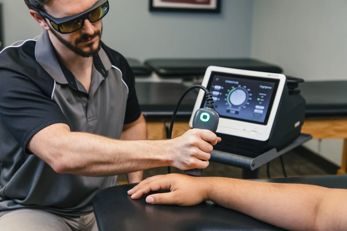 Clinician holding a LightForce handpiece beside the patient and console
