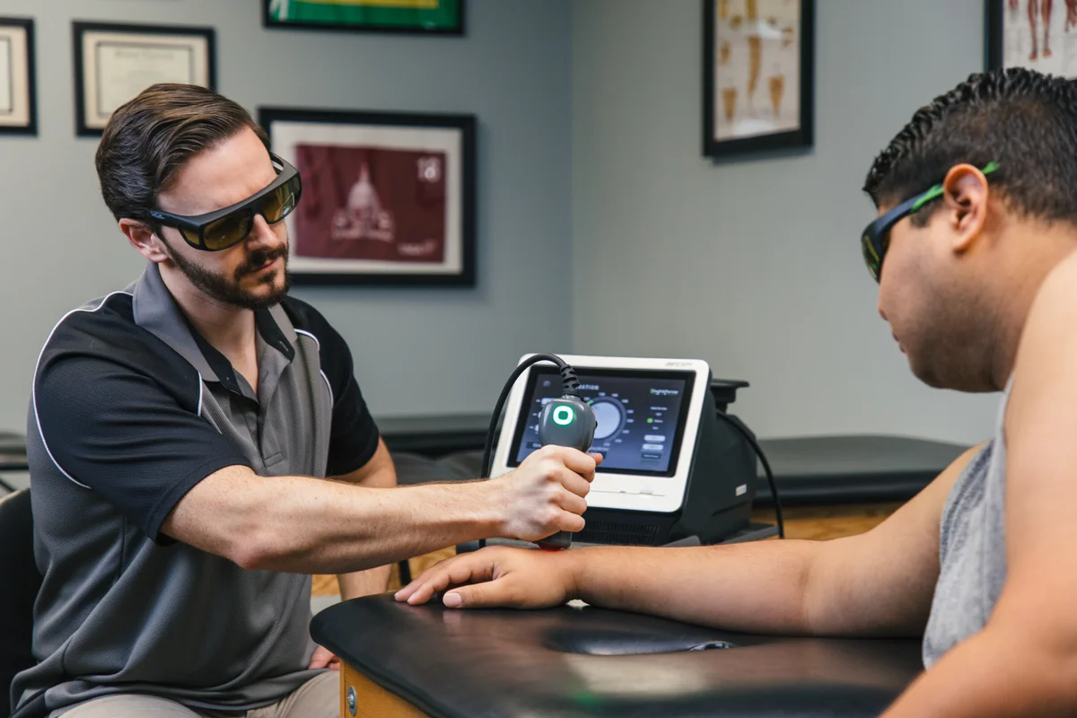 Clinician and patient wearing protective eyewear beside a LightForce laser system