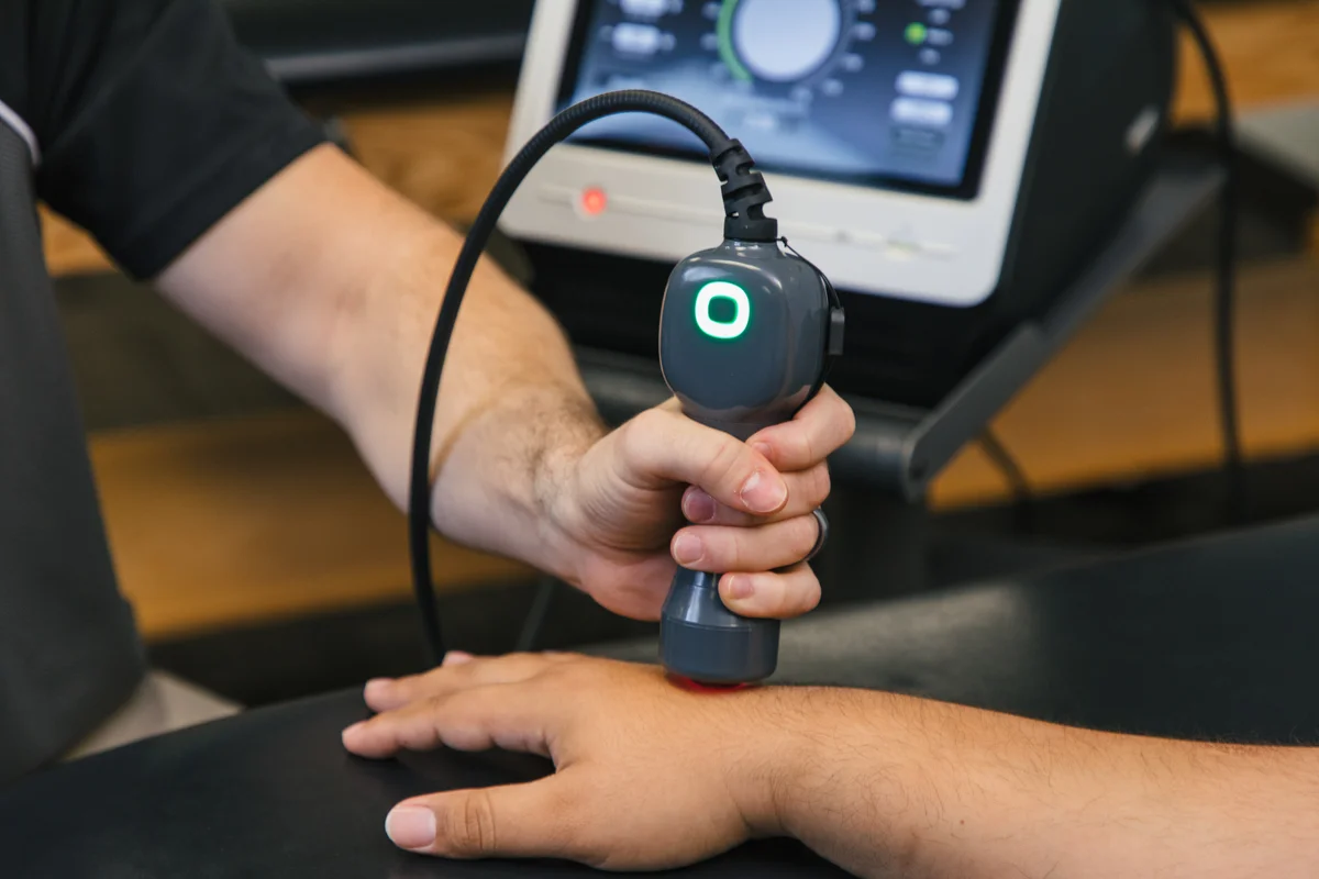 Close-up of a LightForce handpiece and treatment head at a patient’s wrist