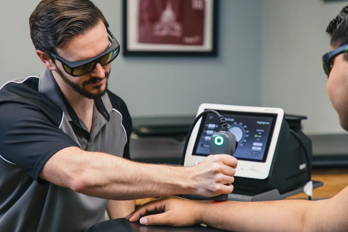 Clinician demonstrating a LightForce laser handpiece beside the system controls